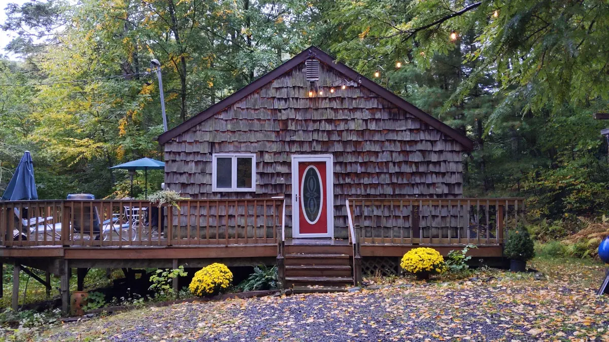 The red front door of the cabin with string lights on an autumn evening